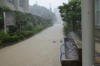 本館横から校門に向かって川のように泥水が流れる様子