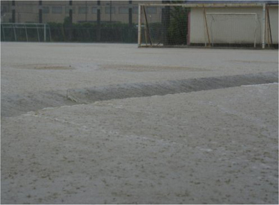 グラウンドから段差のある校地に雨水が流れる様子